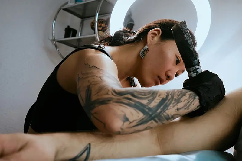 Tattooist tattooing design on customer