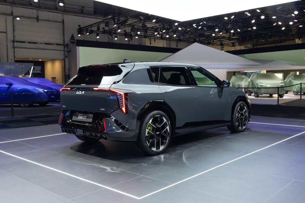 KIa EV4 GT halvkombi sedd snett bakifrån i mässmijö.