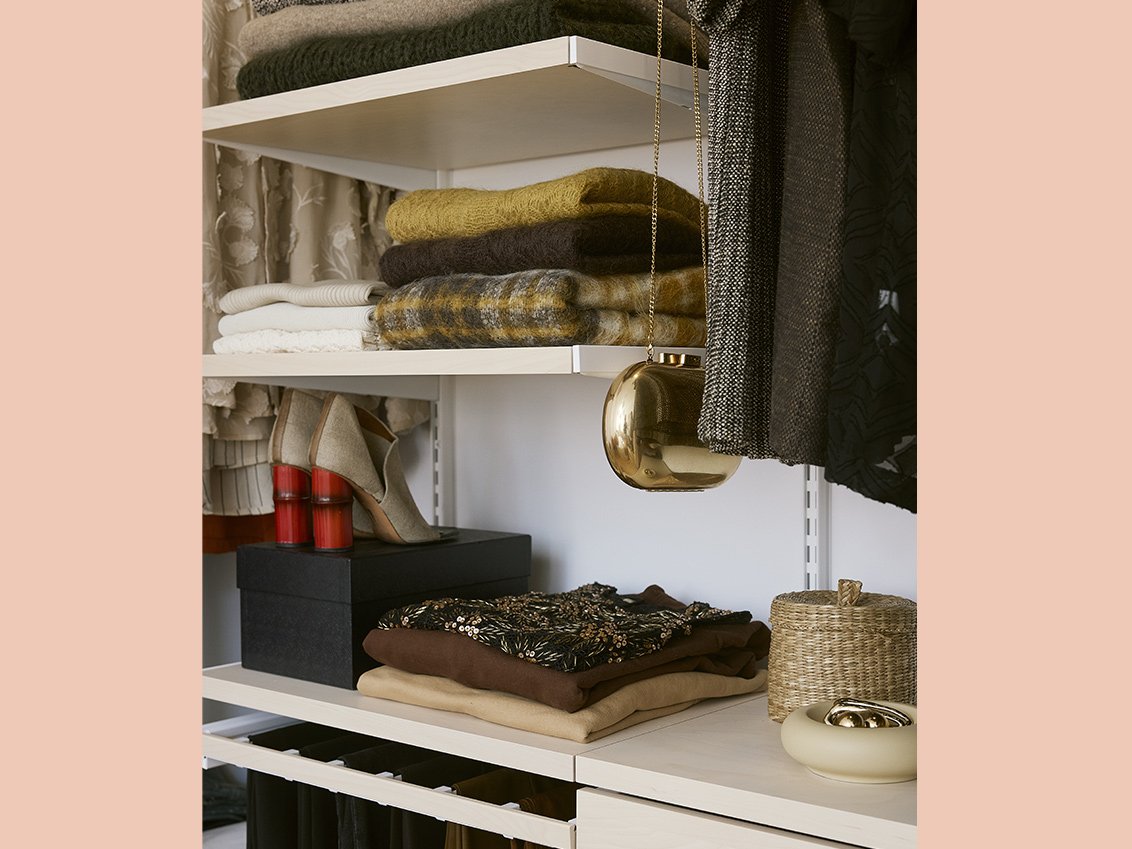 Kläder och accessoarer i en Décor+ by Elfa garderob i vitt och björk.