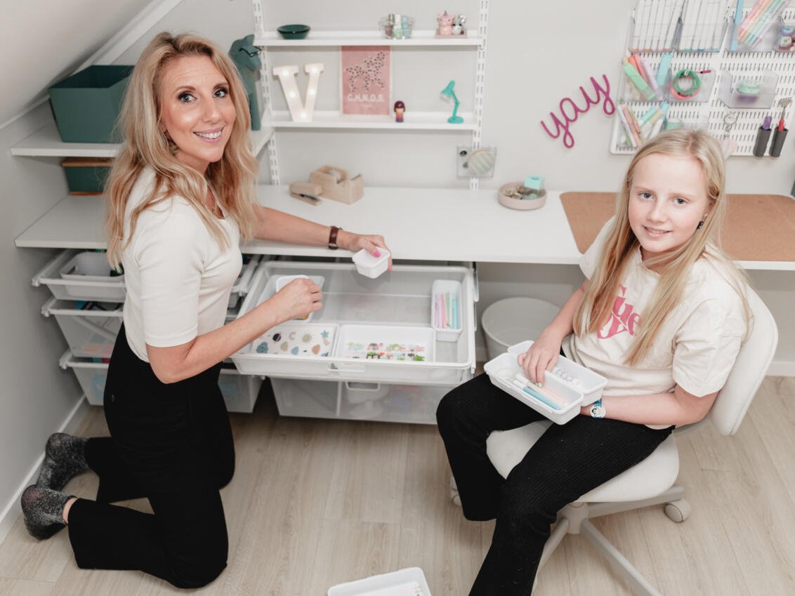 Jenny och Vera sitter vid en utdragen meschback från Elfa med pysselsaker.